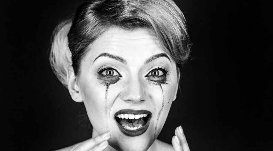 Woman drama and shock concept. Girl cry with mascara streams on face. Woman with shocked face with makeup on grey background, copy space