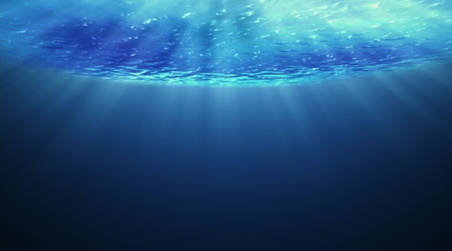 Beautiful underwater sea scene view  and ripples with sun light beams shining from above coming through the deep clear blue water causing a beautiful ocean waves ripple.